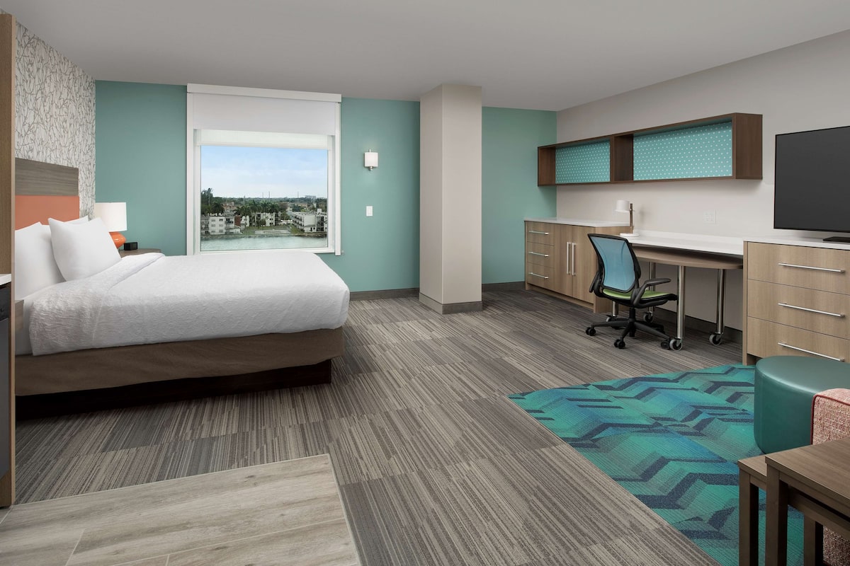 A hotel room with a bed, desk, and TV.