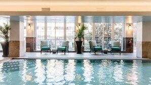 An indoor swimming pool with four chairs and potted plants. - The Read House Hotel Historic Inn and Suites (Chattanooga)