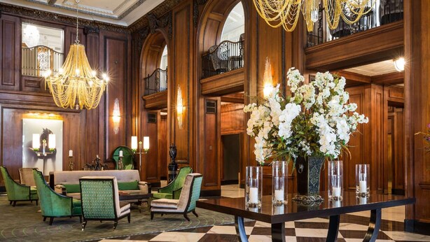 A lobby with a checkered floor, a central table with a vase of flowers, green upholstered chairs, and a chandelier. - The Read House Hotel Historic Inn and Suites (Chattanooga)