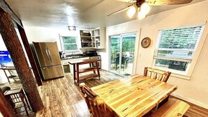 A spacious kitchen with a dining area, large windows, and a ceiling fan.