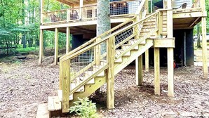 A wooden cabin with a two-story deck and a staircase.