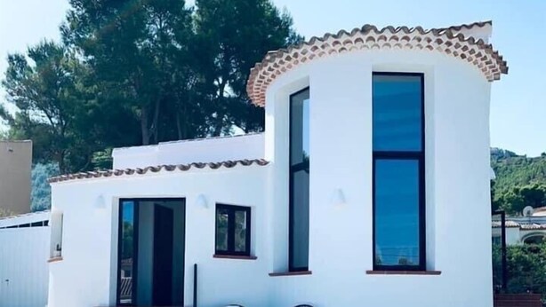 Un edificio blanco con tejado de baldosas y una piscina delantera.