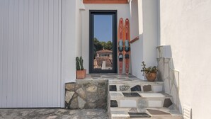 Un edificio blanco con puerta negra, escalones de piedra y dos macetas.