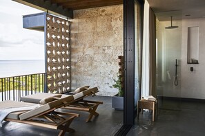 A balcony with sun loungers, a stone wall, and a glass shower enclosure.