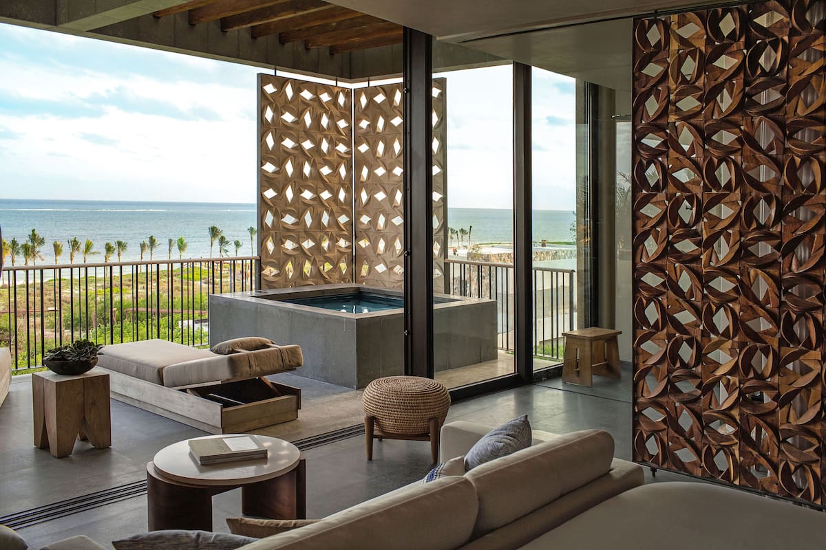 A modern living room with a large sliding glass door leading to a balcony with a view of the ocean.