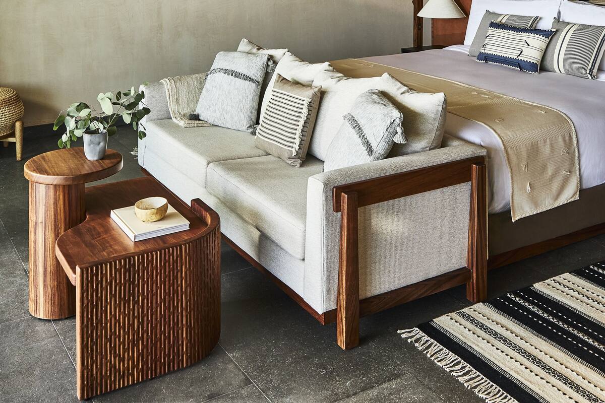 A modern bedroom with a bed, a sofa, a coffee table, and a ceiling fan.