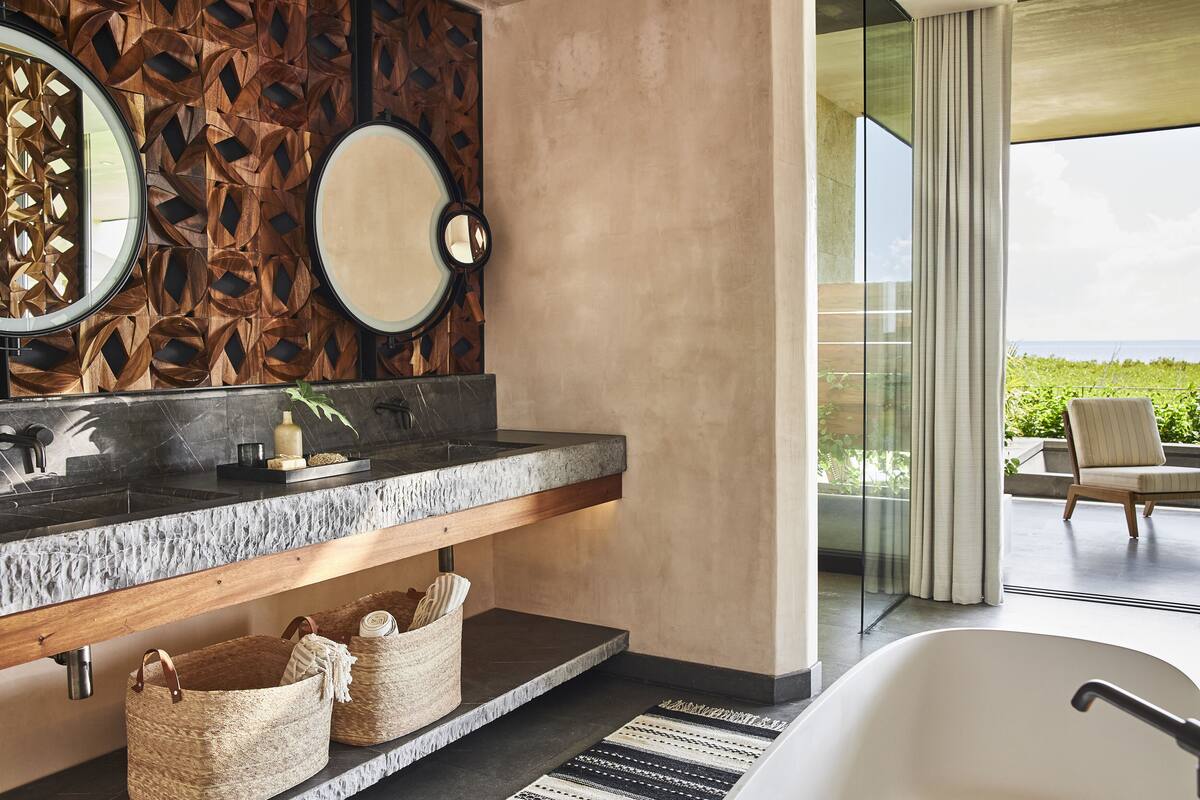 A modern bathroom with a stone countertop, a large mirror, and a bathtub.
