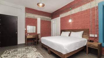 A modern bedroom with a wooden bed, a desk, and a patterned rug.
