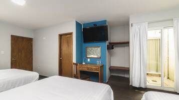 A hotel room with two beds, a desk, a television, and a sliding door to the balcony.