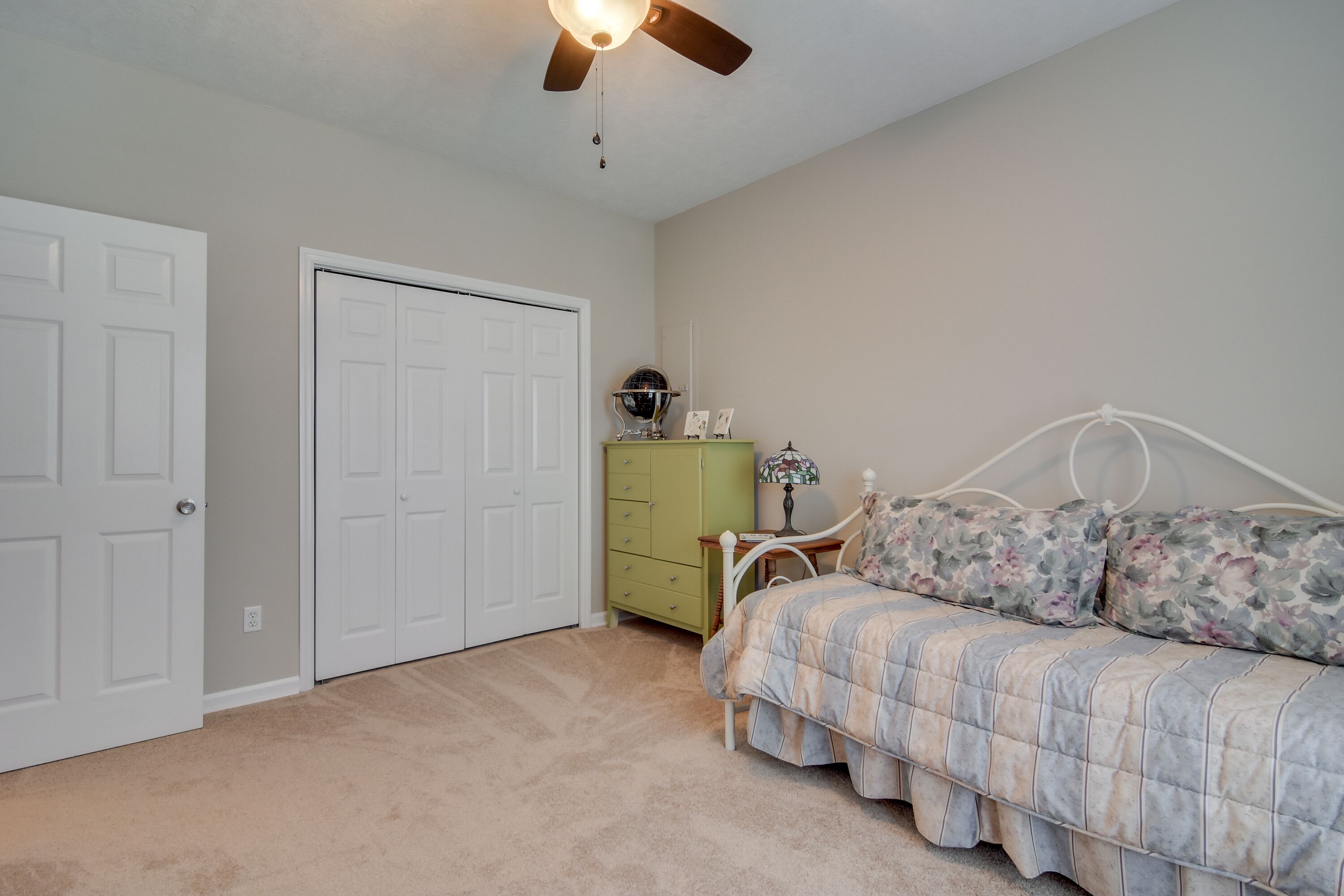 A bedroom with a bed, dresser, and two doors.