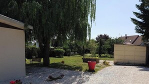 A residential garden with a gravel path, a bench, and a red flower pot. - Charming little house "LA BIKOK (BILLY)