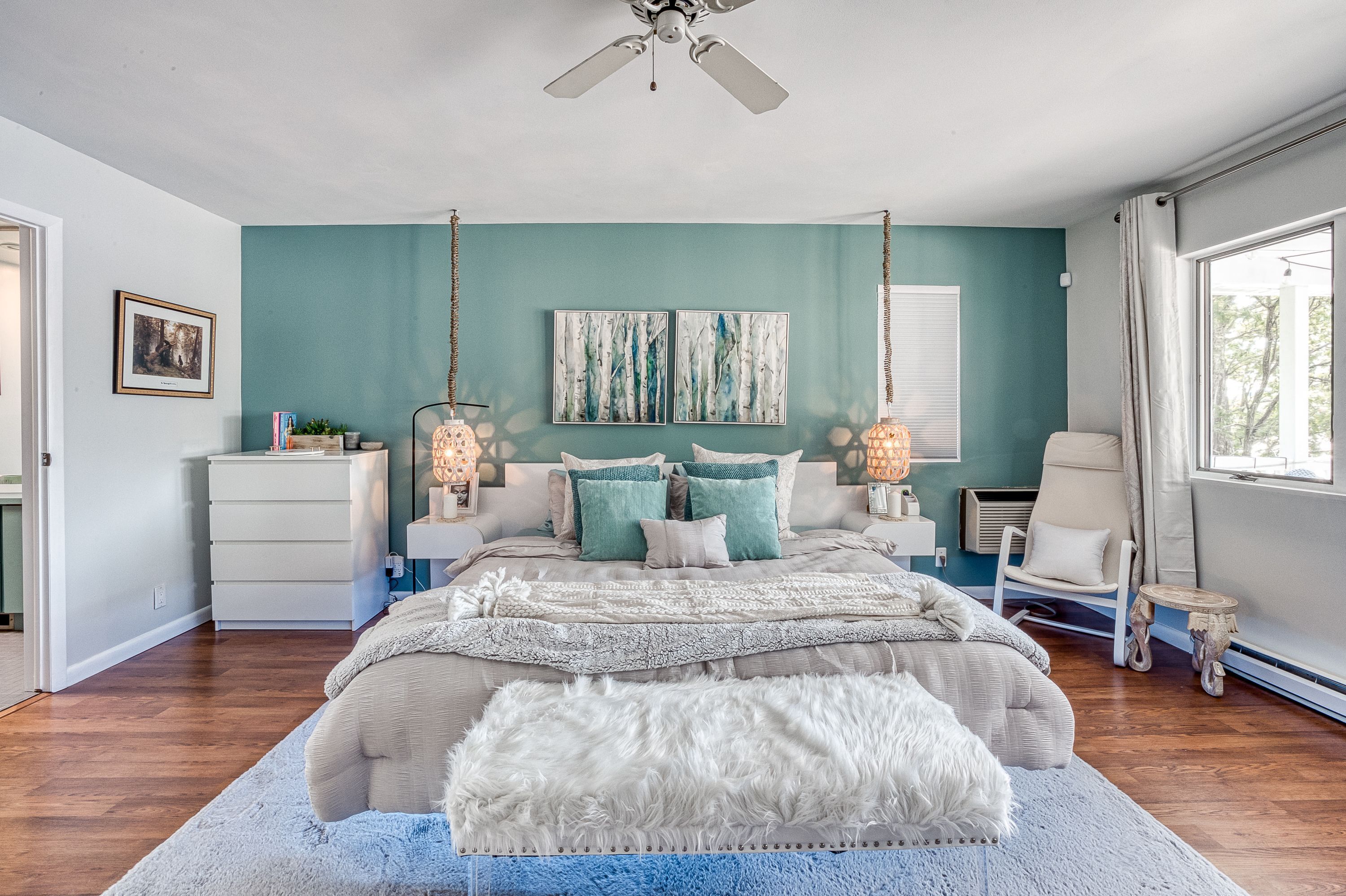 A bedroom with a bed, nightstands, a chair, and artwork on the wall.