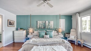 Un dormitorio con cama, mesitas de noche, una silla y una obra de arte en la pared.