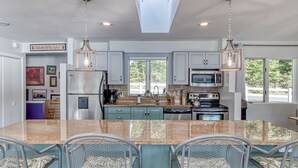 Una cocina moderna con encimeras de granito, electrodomésticos de acero inoxidable y una isla central con taburetes.