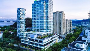 A modern hotel with a prominent sign, multiple floors, and a rooftop terrace. - Holiday Inn One Thousand Island Lake by IHG (Hangzhou)