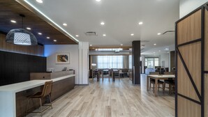 A modern office space with a reception desk, wooden flooring, and a large window providing natural light. - Staybridge Suites Flowood Nw Jackson by IHG (Flowood)
