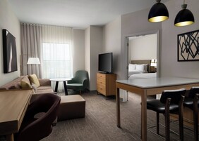 A hotel room with a sofa, a small table, a television, a desk, and a chair.