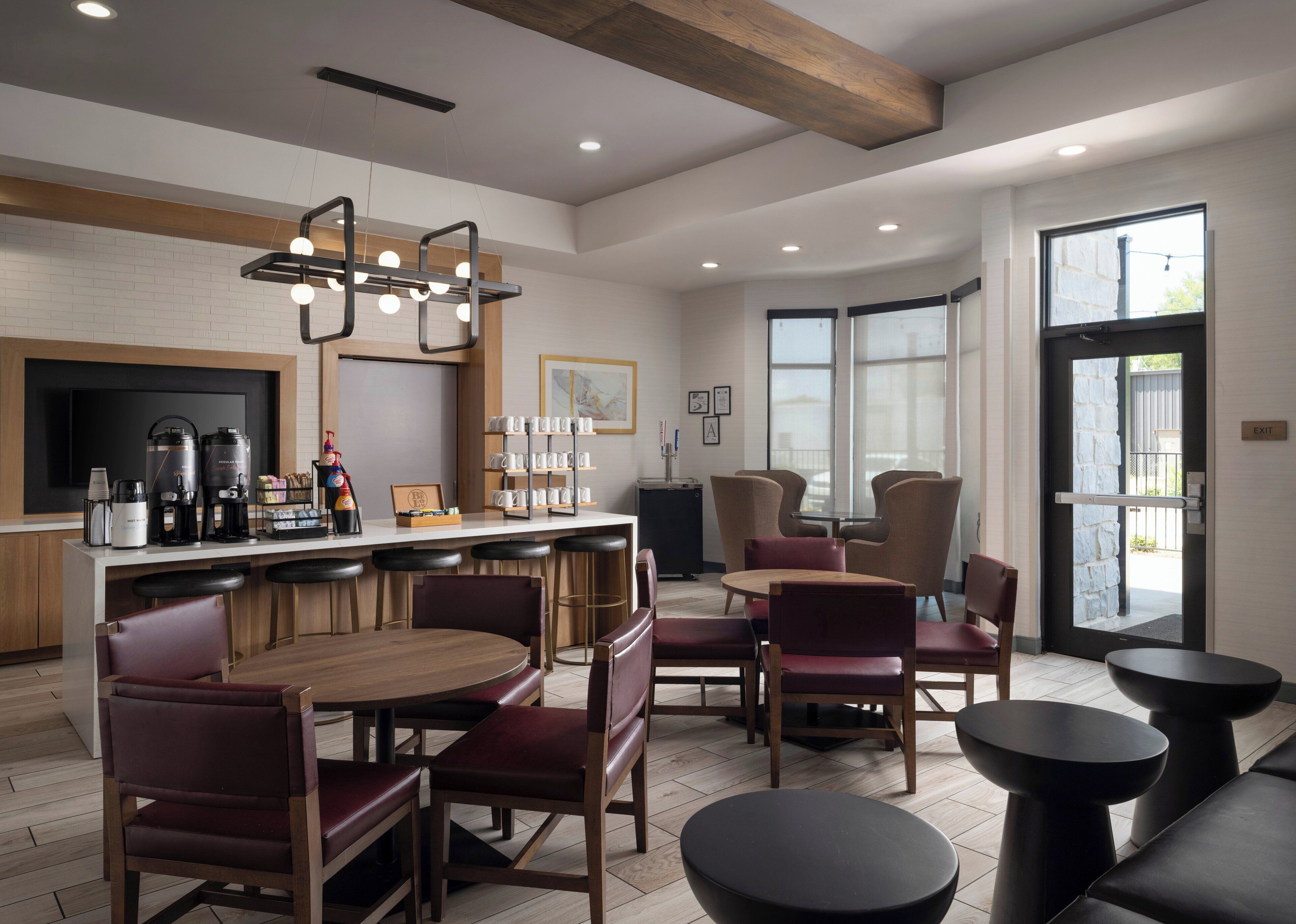 A modern hotel lobby with a bar area, seating arrangements, and a large window providing natural light.