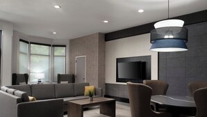 A modern living room with a grey sofa, a coffee table, and a TV mounted on the wall. - Staybridge Suites Flowood Nw Jackson by IHG (Flowood)