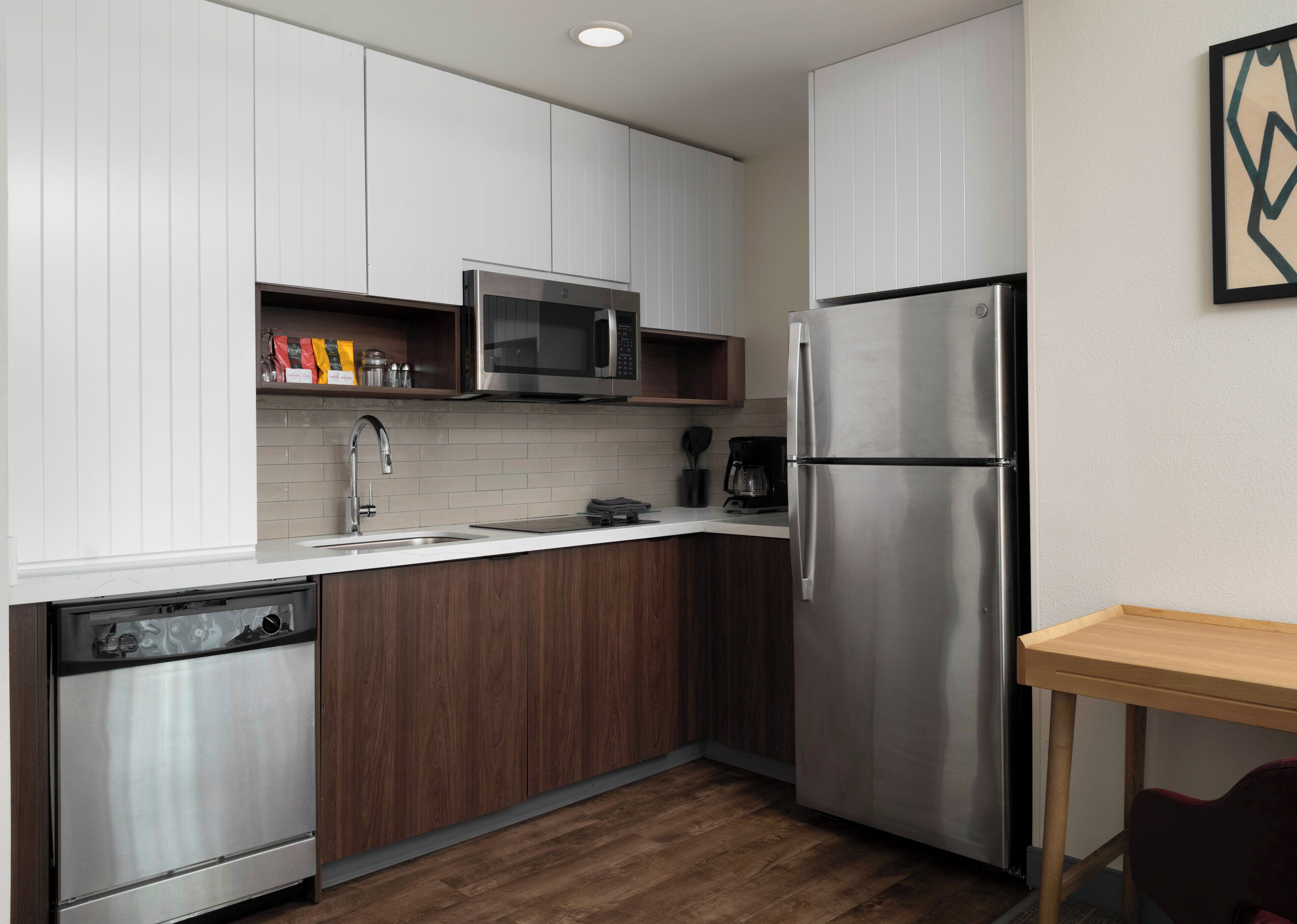 A modern kitchen with white cabinets, stainless steel appliances, and a wooden countertop.