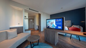 Una sala de estar moderna con un televisor de pantalla plana, un sofá, una mesita y una butaca roja.