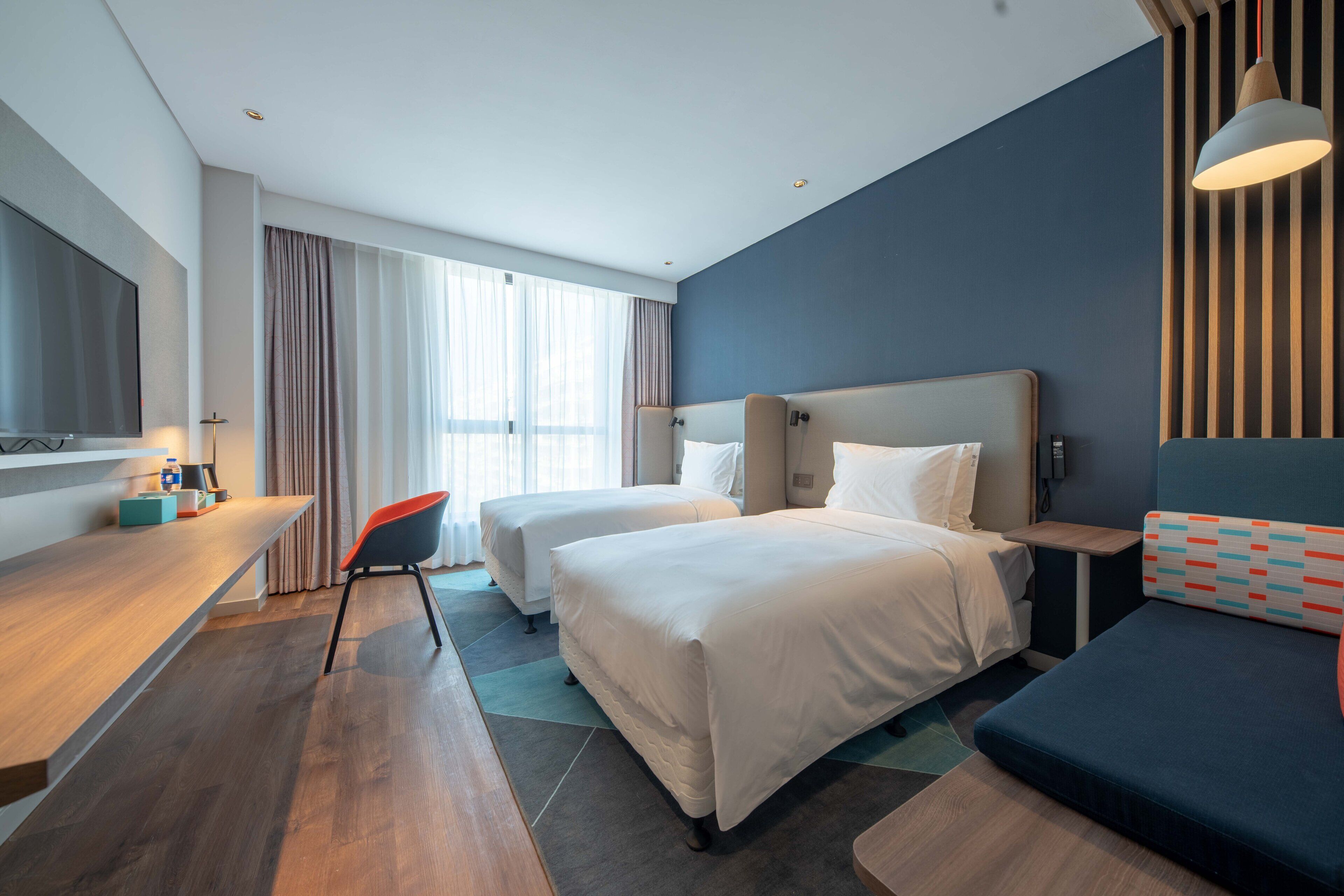 Habitación de hotel con dos camas, un escritorio, una silla y un sofá.