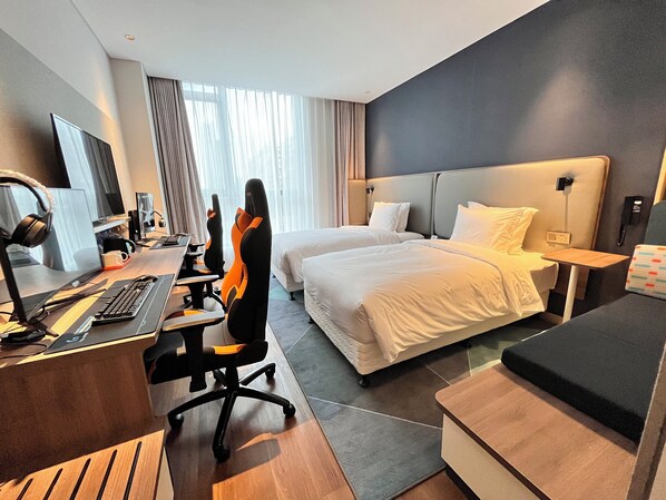Una habitación de hotel con escritorio, dos camas, una silla, televisor y teléfono.