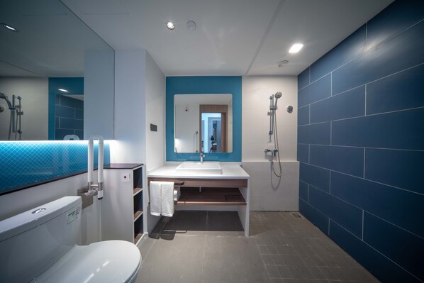 A modern bathroom with a white toilet, a sink with a blue-tiled backsplash, and a shower area. - Holiday Inn Express Nantong North Gateway by IHG (Nantong)