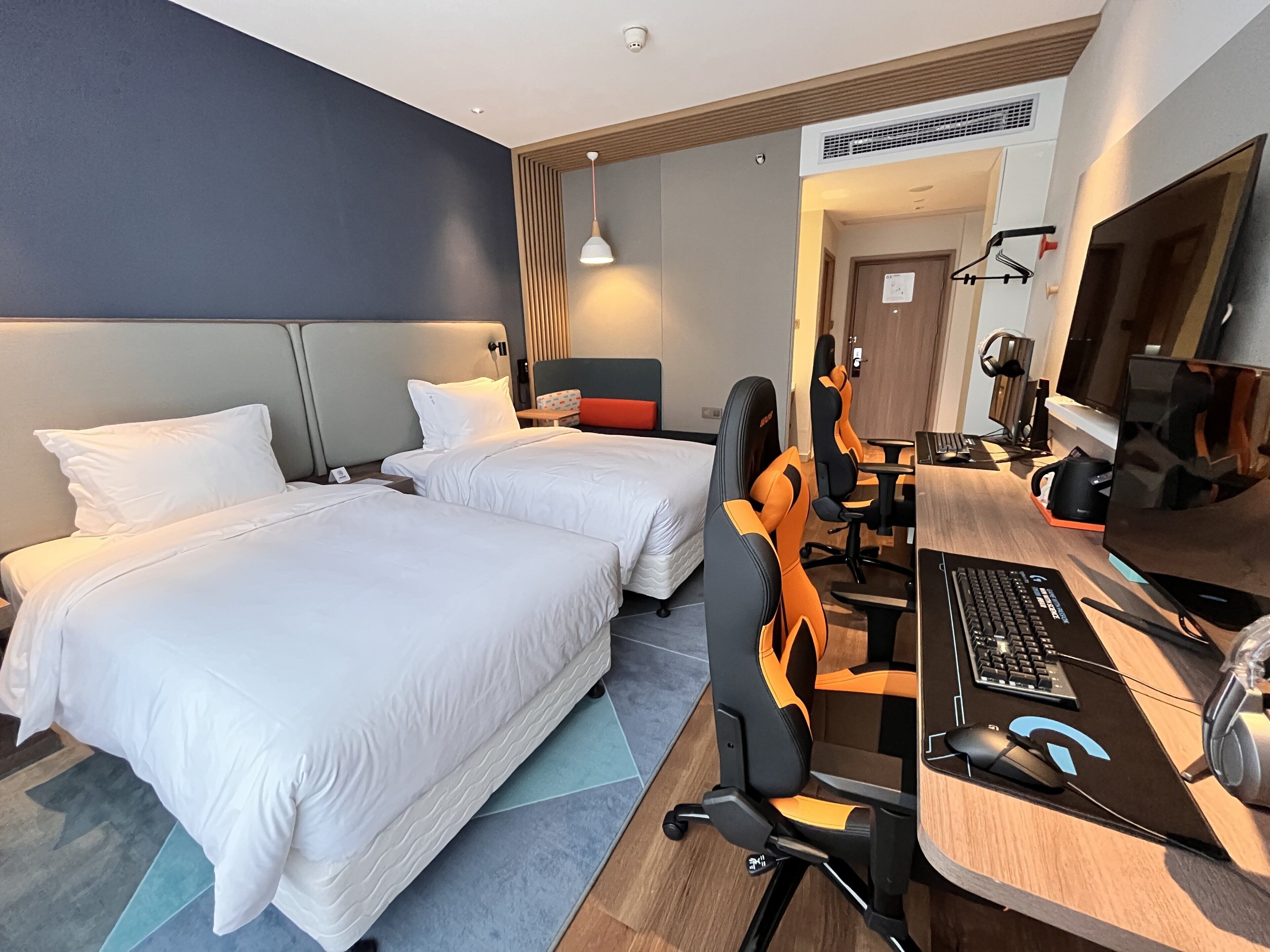 A hotel room with two beds, a desk with a computer, and a TV.