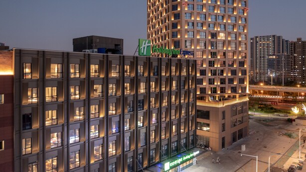 Un moderno edificio de hotel con varios pisos, amplias ventanas y un cartel llamativo de Holiday Inn Express.