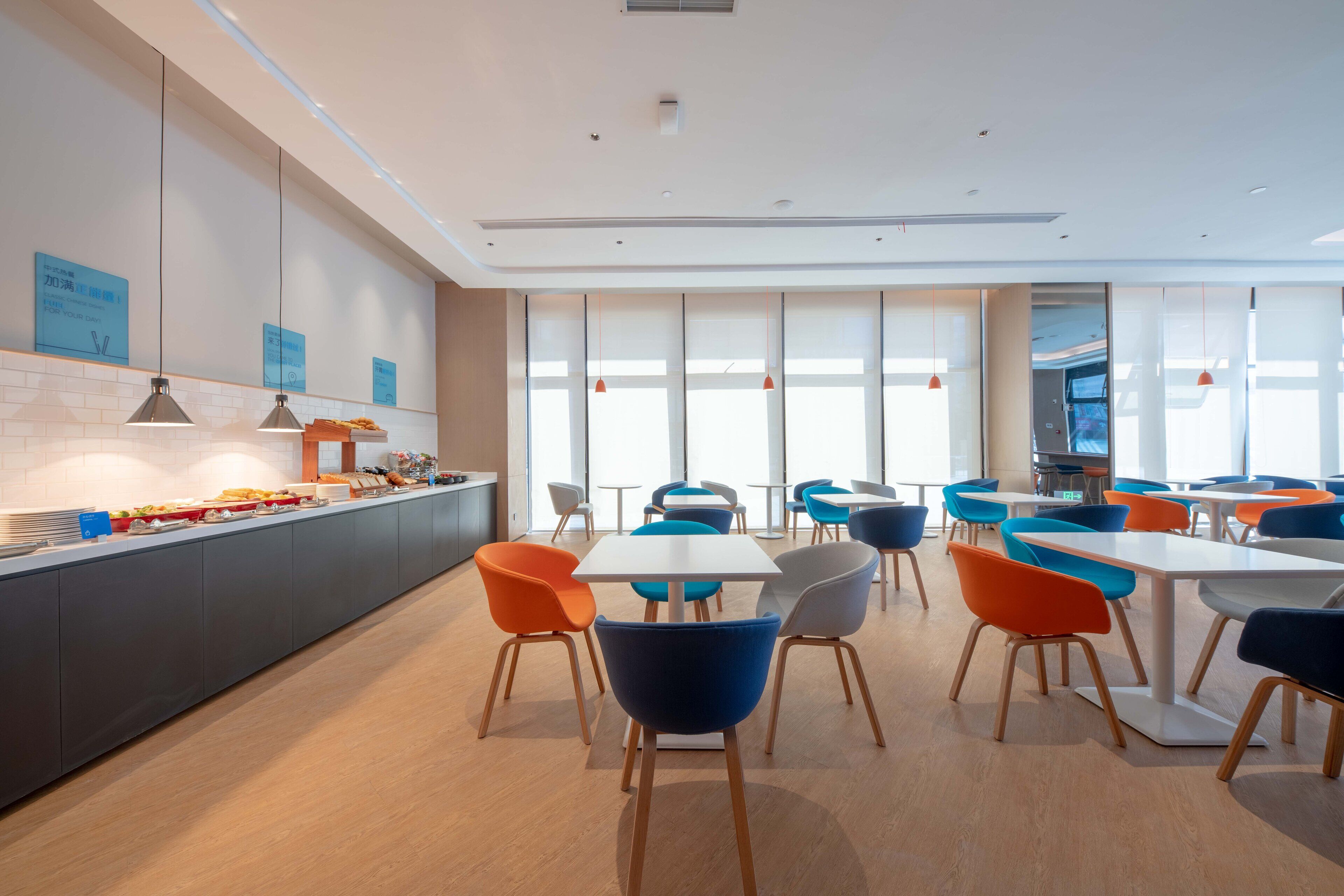 A modern dining area with a long counter, multiple tables, and colorful chairs.