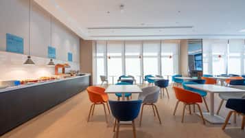 A modern dining area with a long counter, multiple tables, and colorful chairs.