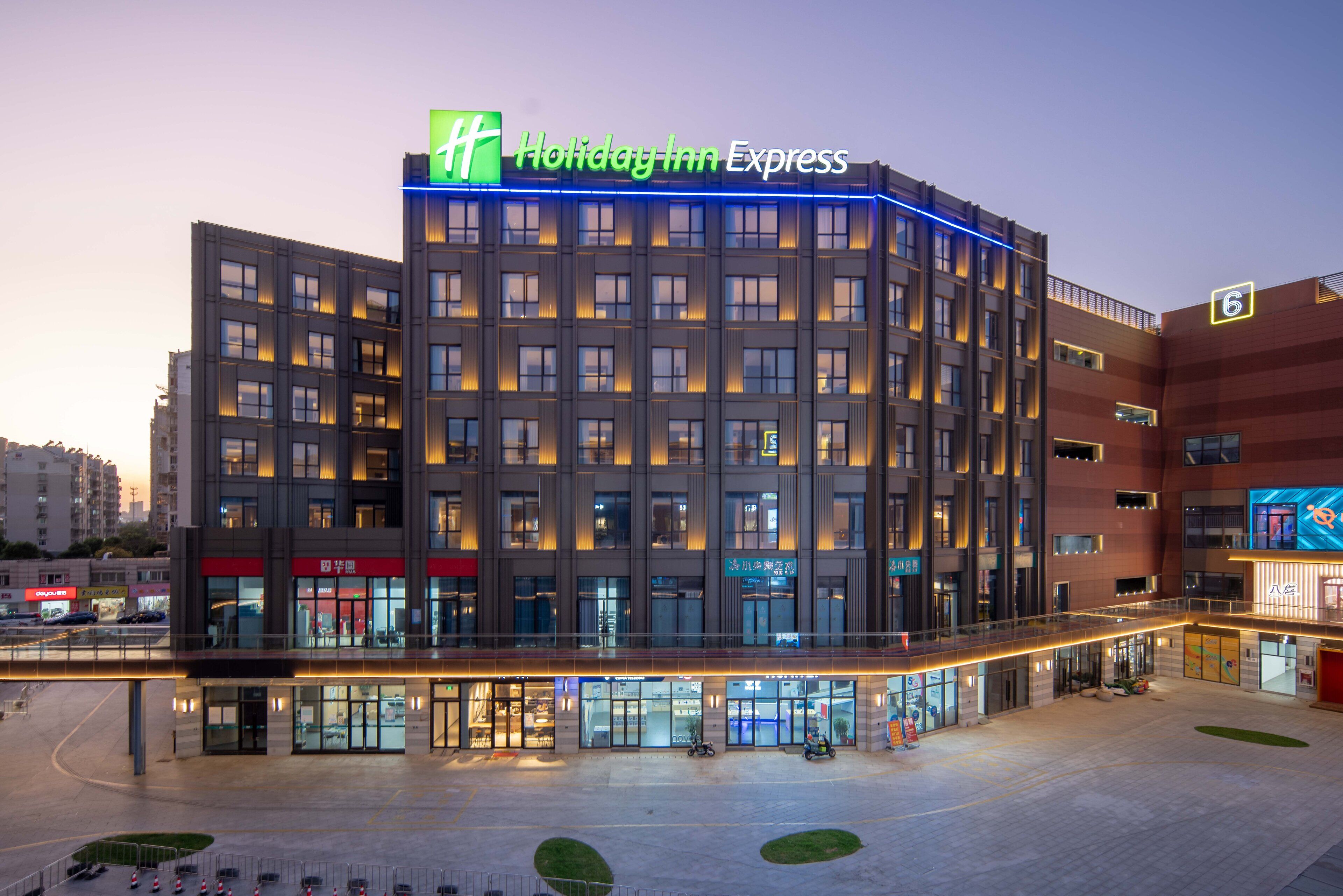 Ein Holiday Inn Express Gebäude mit modernem Design, mit auffälligem Schild, mehreren Etagen und einem großzügigen Eingangsbereich.