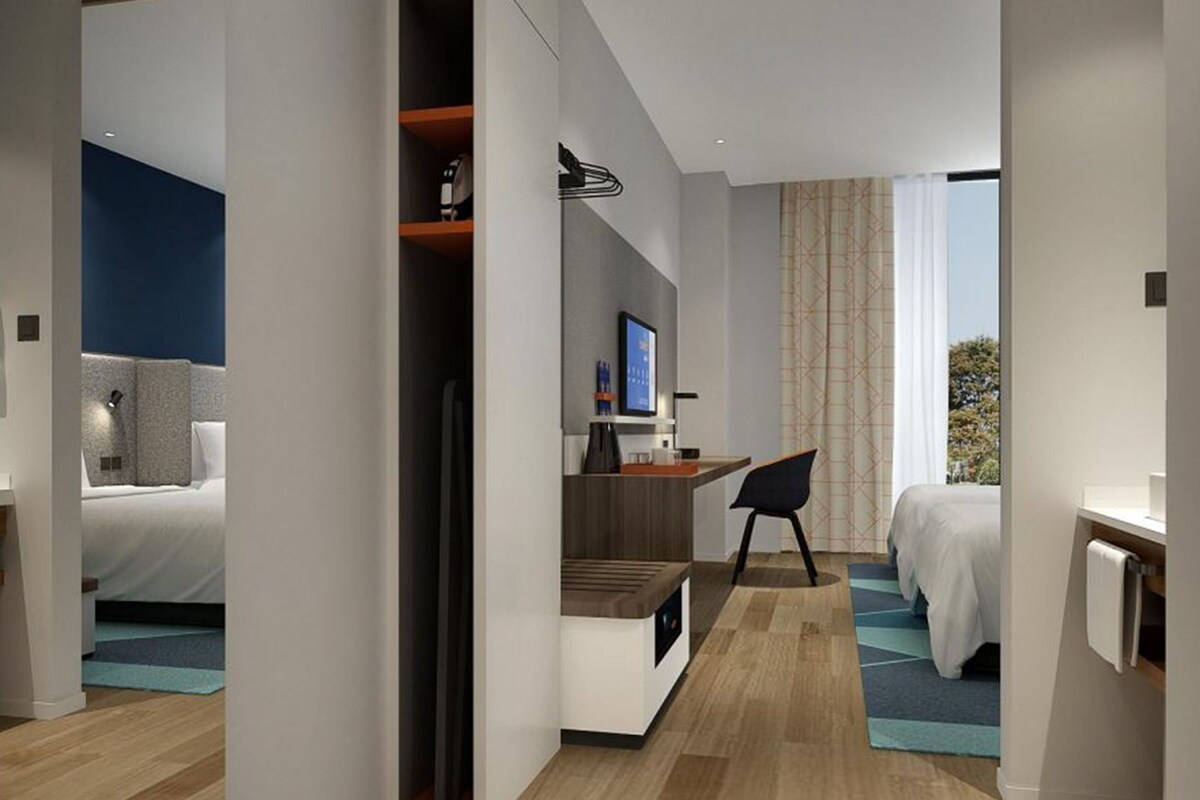 A modern hotel room with a bed, desk, and seating area.