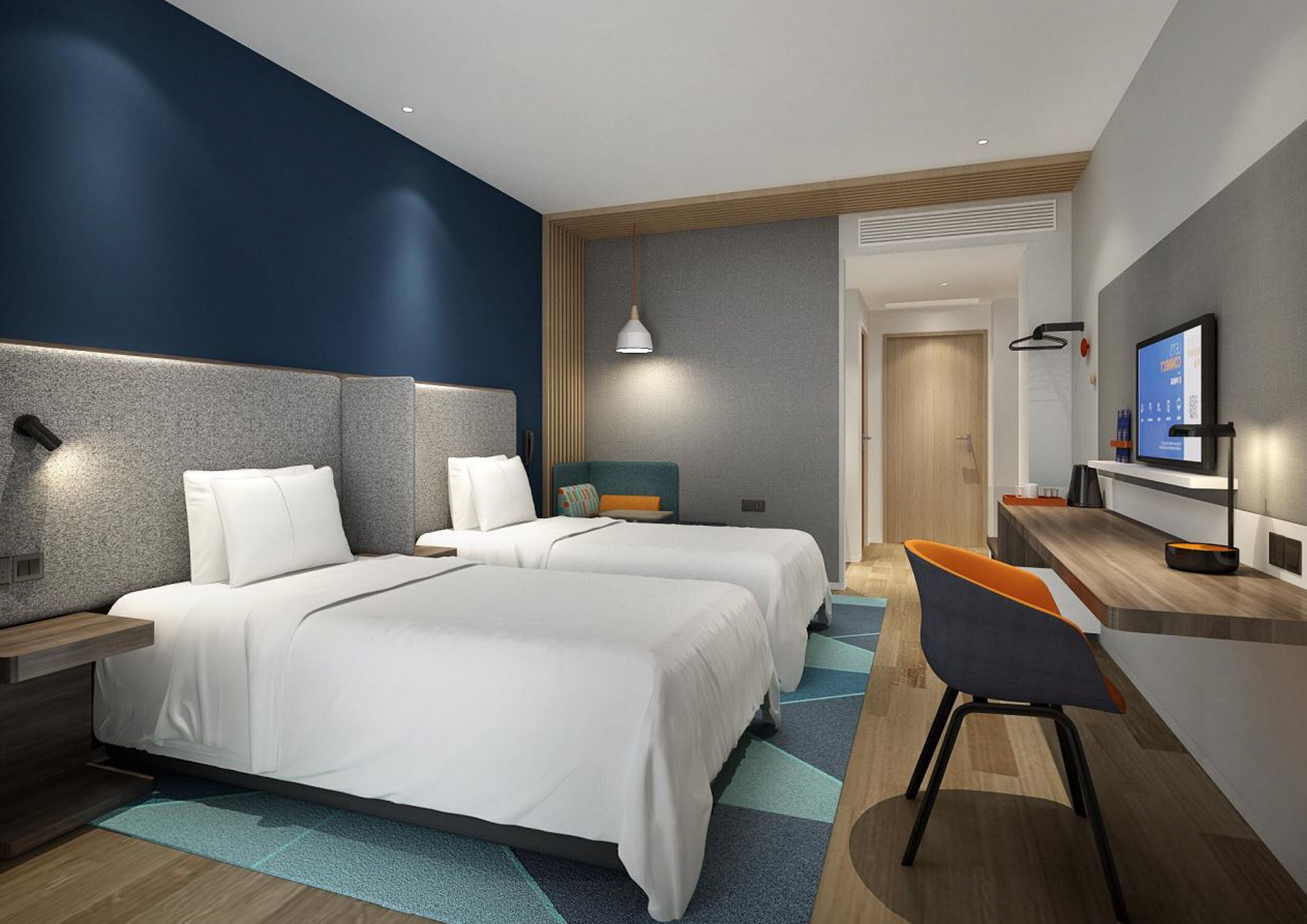 A modern hotel room with two beds, a desk, a chair, a TV, and a bathroom visible through an open door.