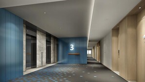 Un pasillo moderno con una pared azul decorativa, un cartel con el número 3 y un suelo estampado.