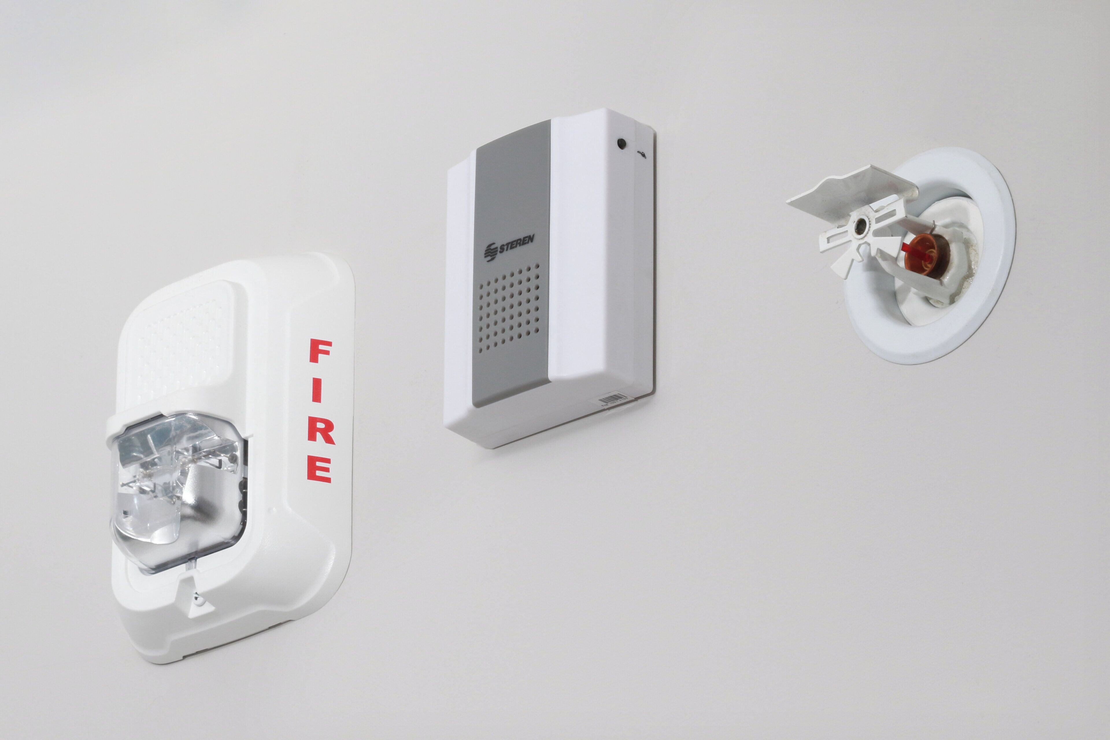 A fire alarm system with a clear 'FIRE' label, a control panel, and a smoke detector.