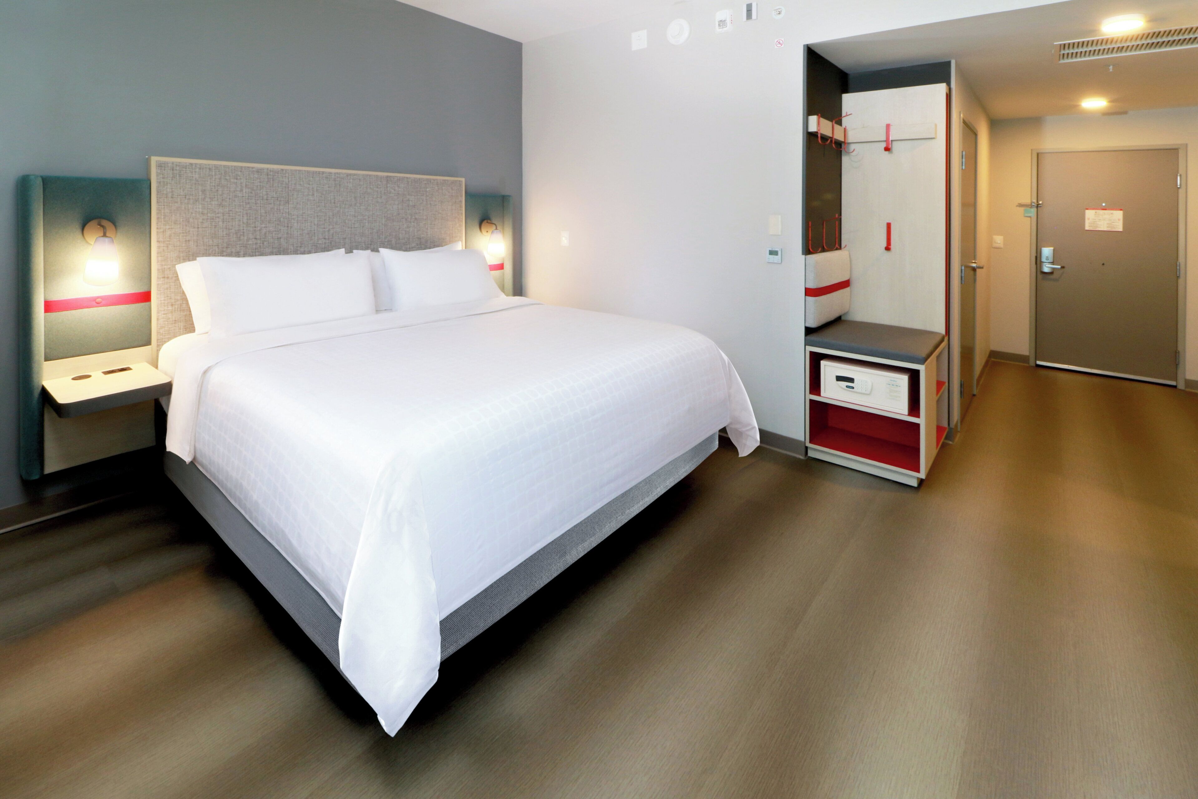 Una habitación de hotel con una cama grande, mesitas de noche, un armario y una puerta.