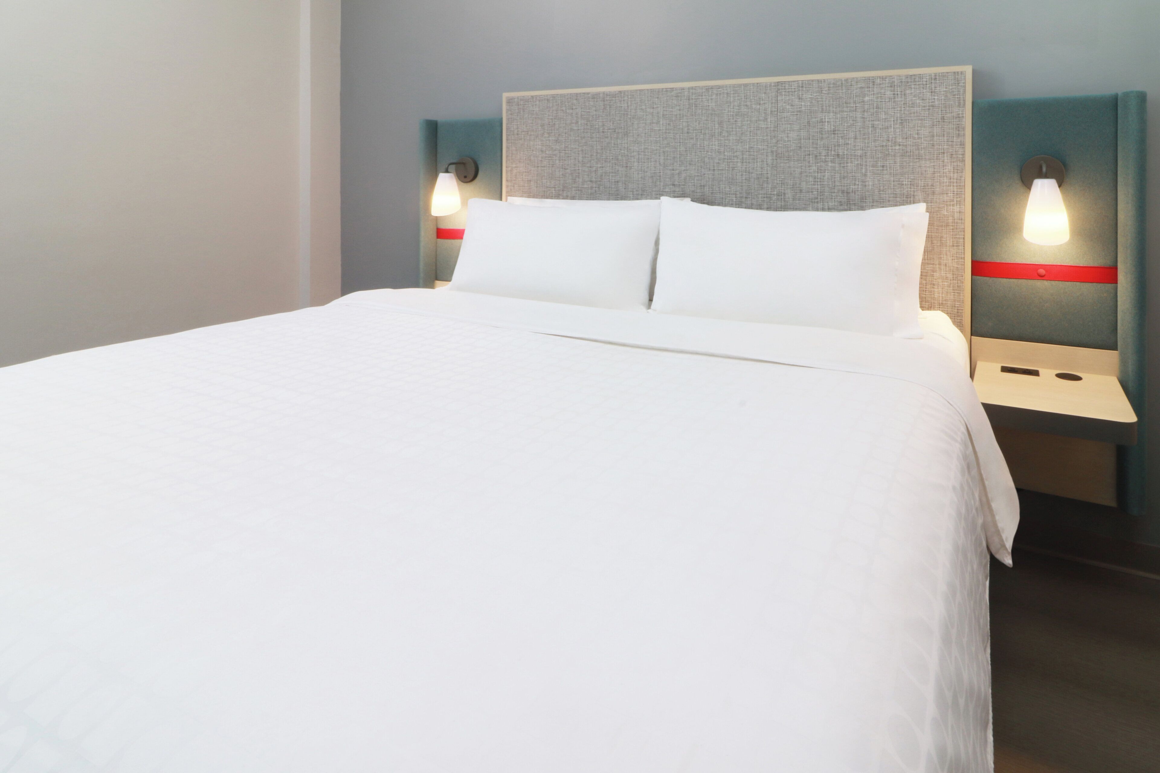 Cama bem arrumada com lençóis brancos em um quarto de hotel.