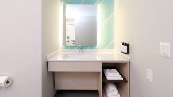 Un baño moderno con un lavabo blanco, un espejo y un estante para toallas.