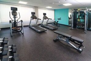 Une salle de sport équipée de tapis de course, d’un banc et d’appareils de musculation.