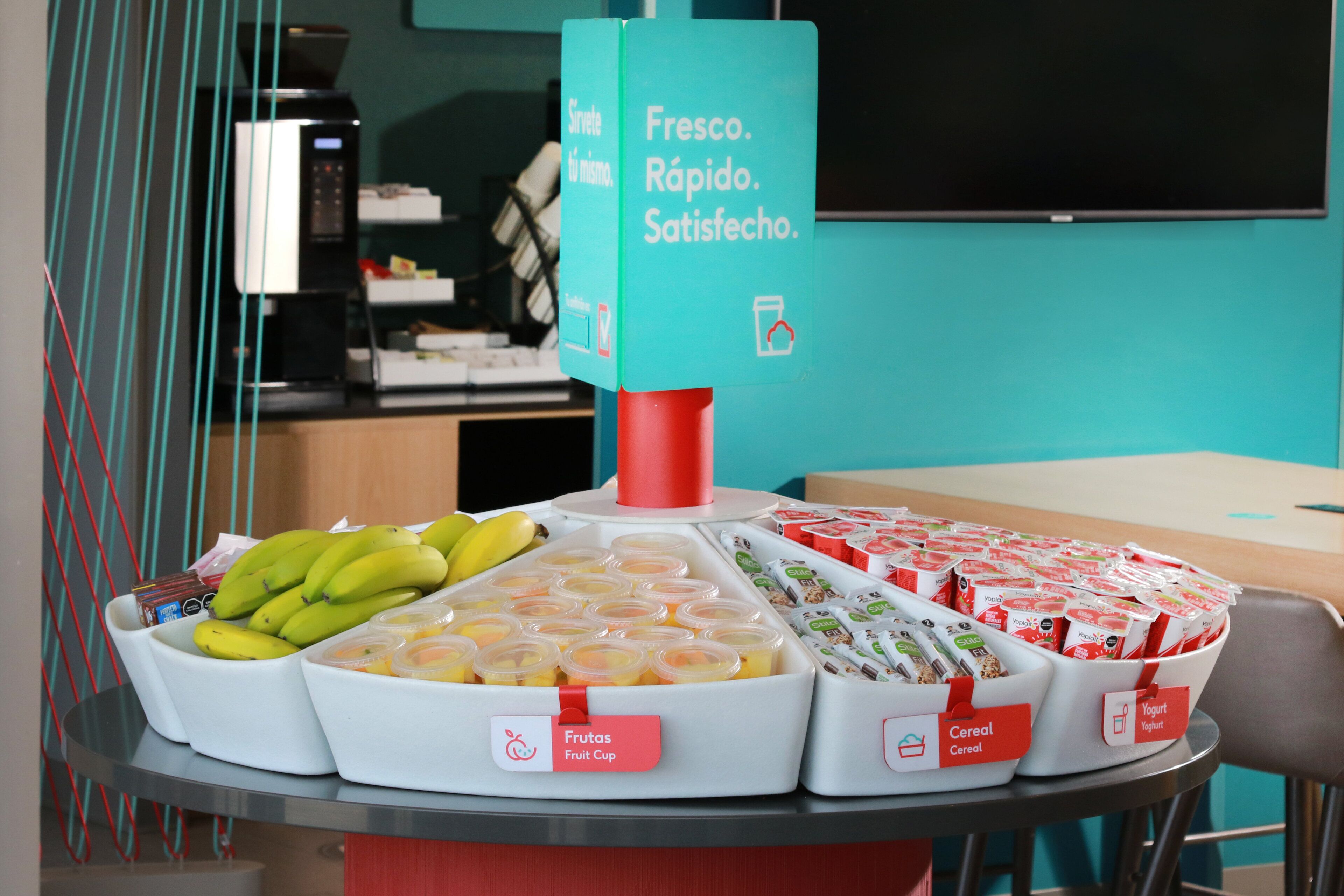 A breakfast buffet with labeled food sections including fruits, cereal, and yogurt.