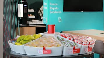 A breakfast buffet with labeled food sections including fruits, cereal, and yogurt.