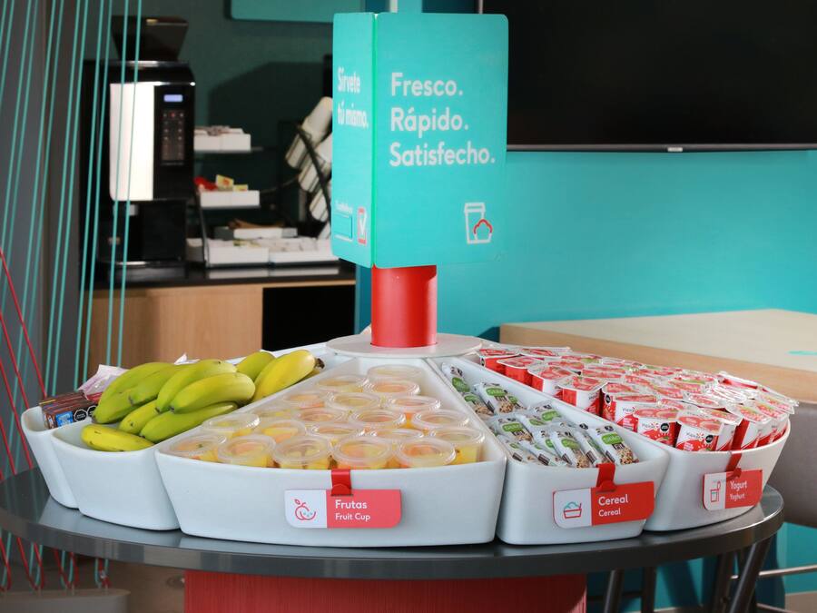 A breakfast buffet with labeled food sections including fruits, cereal, and yogurt.
