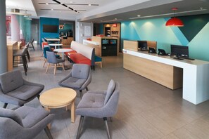 Un hall d’hôtel moderne, doté d’espaces aménagés avec des sièges, d’un comptoir d’accueil et d’une machine à café.