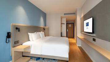 A hotel room with a bed, bedside table, and a mounted TV.