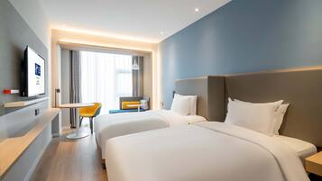 Habitación de hotel con dos camas, un escritorio, una silla y un televisor.