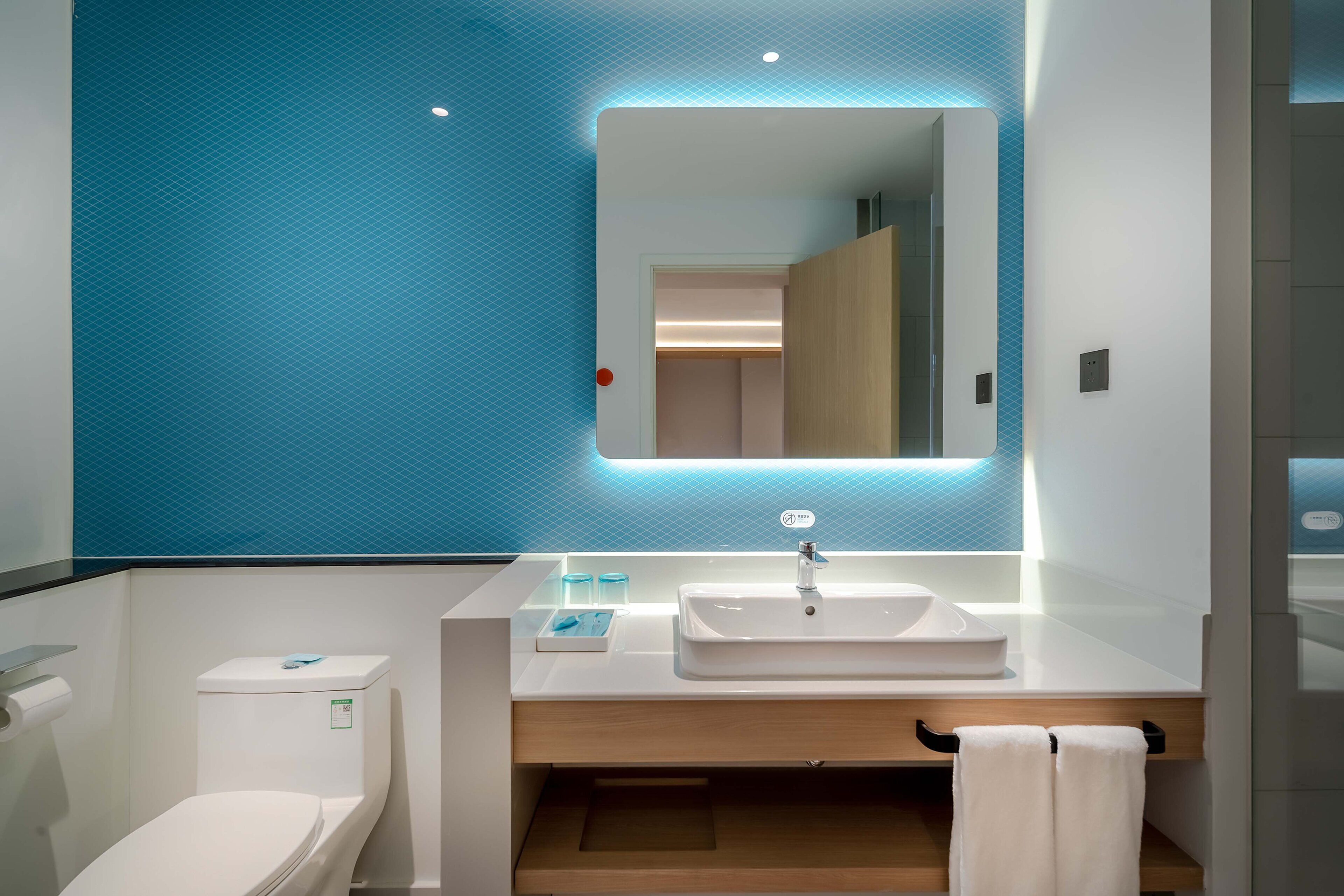 A modern bathroom with a white sink, a mirror, and a blue wall.