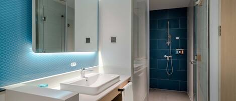 Une salle de bain moderne avec une douche à parois de verre, un lavabo blanc et un grand miroir.