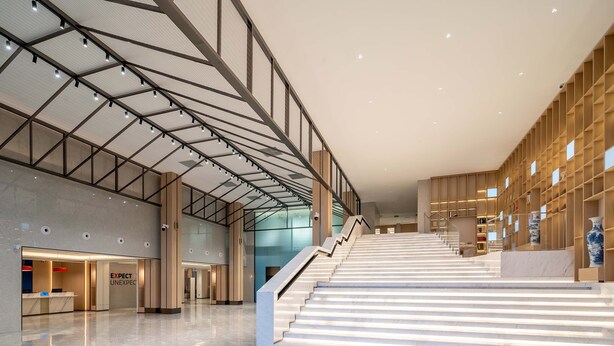 Un vestíbulo espacioso con piso de mármol, una escalera y una zona de recepción.